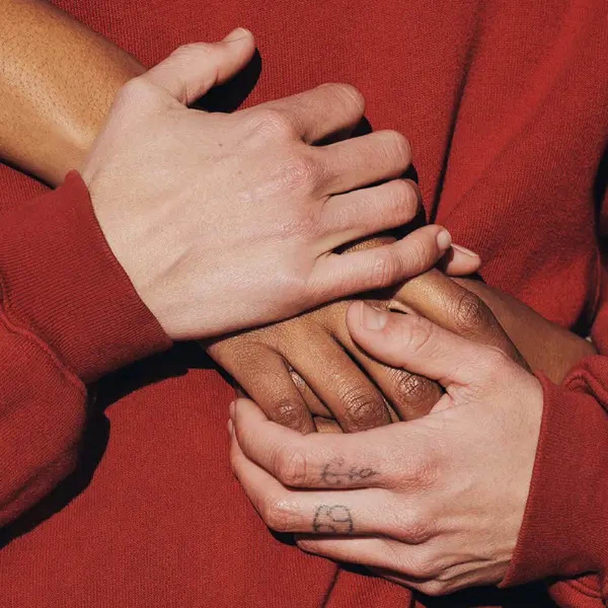 Two pairs of hands holding one another